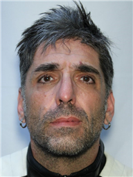 A man with short, gray hair and earrings is shown in a frontal mugshot-style portrait.