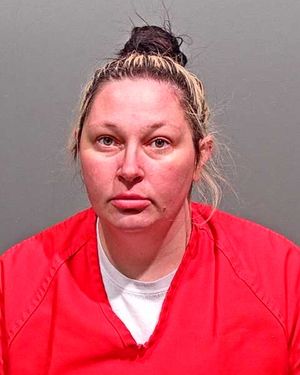 The image shows a woman with light hair pulled back in a bun, wearing a red prison jumpsuit, against a grey background.