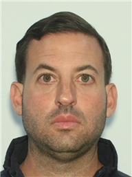 A man with short dark hair and a serious expression is shown in a head-and-shoulders photo.
