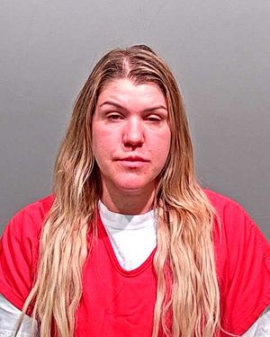 A person with long blonde hair is shown wearing a red jumpsuit and looking directly at the camera.