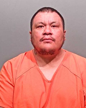 A man wearing an orange prison jumpsuit is facing forward, looking directly at the camera.