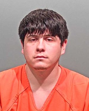A young man wearing an orange prison jumpsuit stares directly at the camera with a neutral expression.