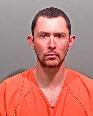 A man in an orange jumpsuit is shown in a mugshot with a neutral expression against a gray background.