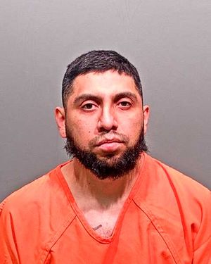 A man wearing an orange prison jumpsuit is looking directly at the camera.
