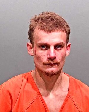 A man with short hair and facial injuries is shown wearing an orange jumpsuit in a mugshot.