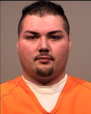 A man in an orange prison jumpsuit poses for a mugshot.
