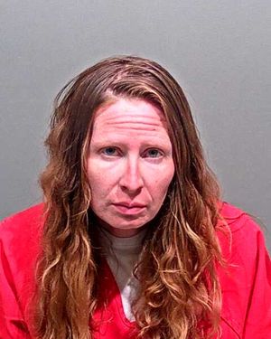A woman with long, wavy hair is shown wearing a red prison jumpsuit against a neutral background.