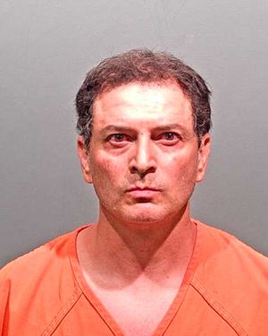 A man wearing an orange prison jumpsuit is photographed against a gray background.