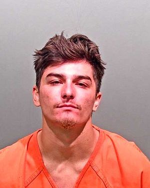 A young man with dark hair is shown in a mugshot wearing an orange prison jumpsuit.