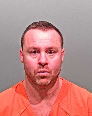 A man wearing an orange prison jumpsuit is facing the camera with a neutral expression.