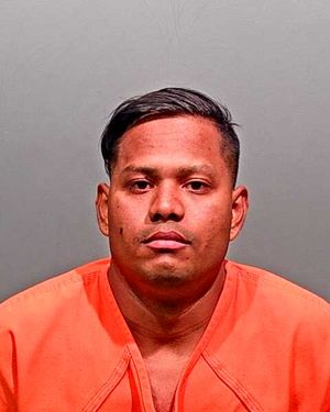 A male individual wearing an orange prison jumpsuit is shown in a mugshot.