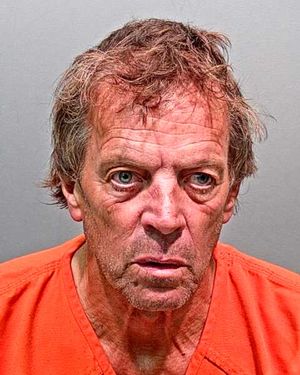 A middle-aged man with unkempt hair is shown in a prison jumpsuit, looking intently at the camera.