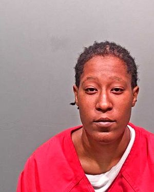 A person wearing a red prison jumpsuit is shown in a mugshot against a plain background.