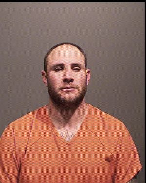 A male individual is shown in a mugshot wearing an orange prison uniform against a plain backdrop.