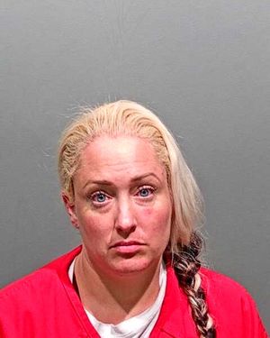 Mugshot of a woman with blonde hair wearing a red prison jumpsuit.
