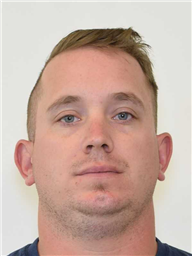 A young man with short hair and a neutral expression is facing the camera.