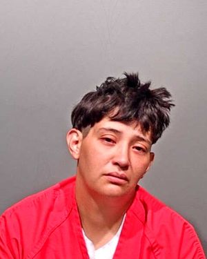A person wearing a red jail uniform is shown in a mugshot with a neutral expression.