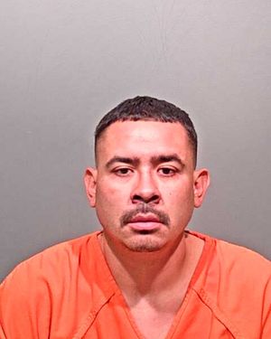 A man wearing an orange prison jumpsuit is shown in a mugshot.