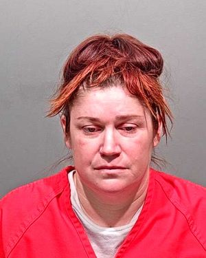 A woman with reddish-brown hair, wearing a red prison jumpsuit, is looking directly at the camera.