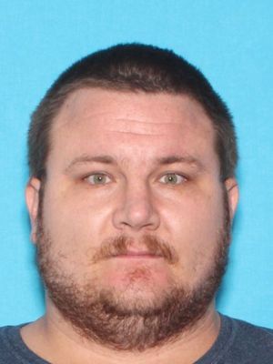 A man with short hair and a beard is shown against a blue background.