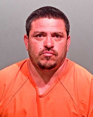 A man in an orange prison jumpsuit is facing the camera with a serious expression.