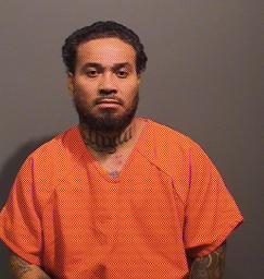A man with tattoos is wearing an orange jumpsuit against a plain background.
